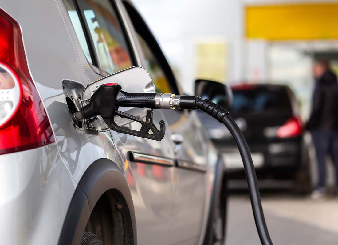 Gas Station Insurance - Close-up View of a Gray Metallic Car Refueling at a Gas Station With Selective Focus and Background Blurred in the Distance