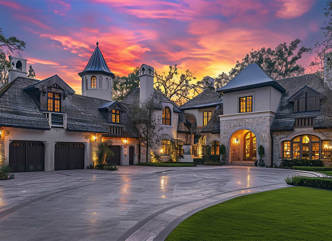 High Net Worth Insurance - Luxury Brick Mansion During the Evening With Lights Showing From the Windows