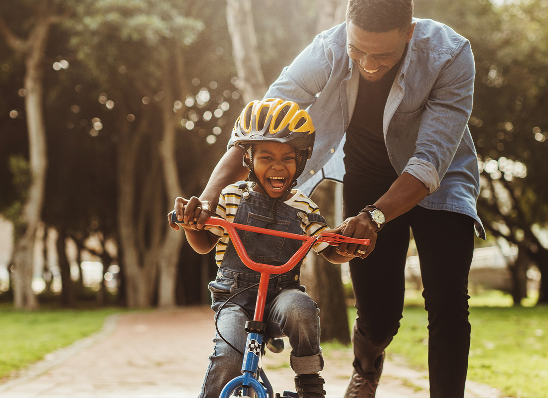 Personal Insurance - Father Teaching His Son Cycling at Park